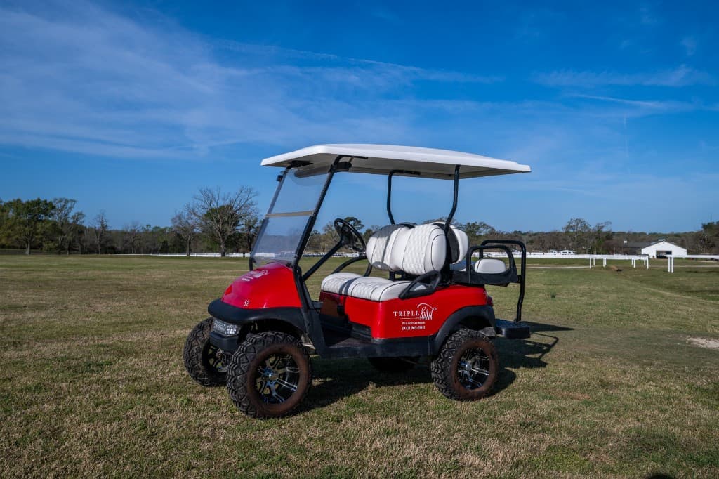 Red Triple W golf cart with a white roof and seats, photographed from the side