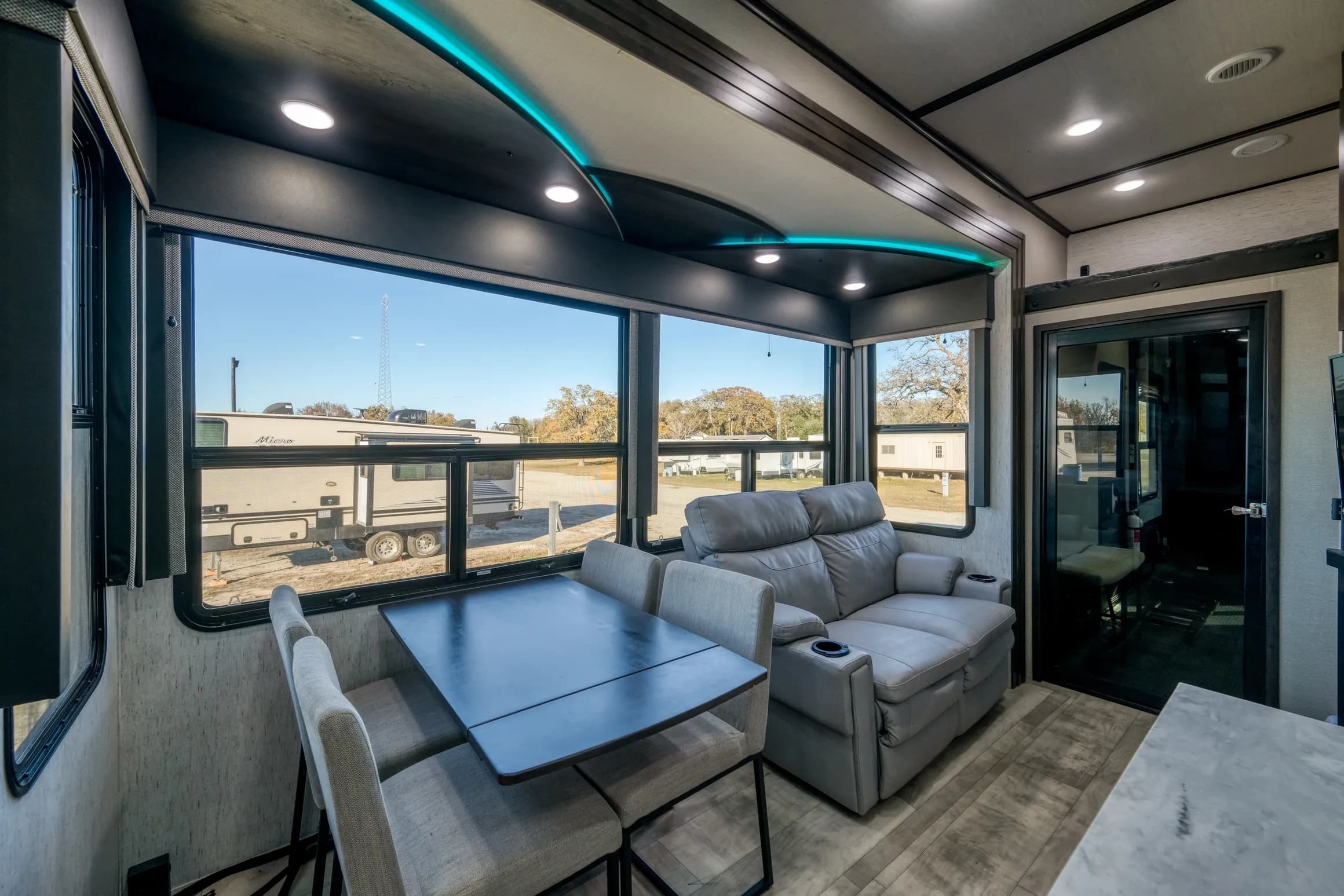 RV living area with a sofa, dinette and large windows